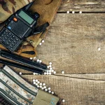 Close up of airsoft gun magazine and airsoft balls on wooden background