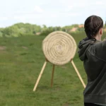 girl shoots from an arrow bow at a straw target in the countryside
