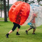 People play bumperball zorbsoccer outdoor. summer time