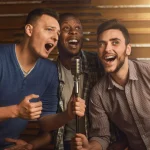 Happy friends singing karaoke together in bar