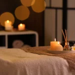 Burning candles and aromatic reed freshener on table in spa salon, space for text