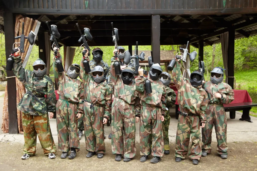 Boys dressed in camouflage stand in a row on a paintball base